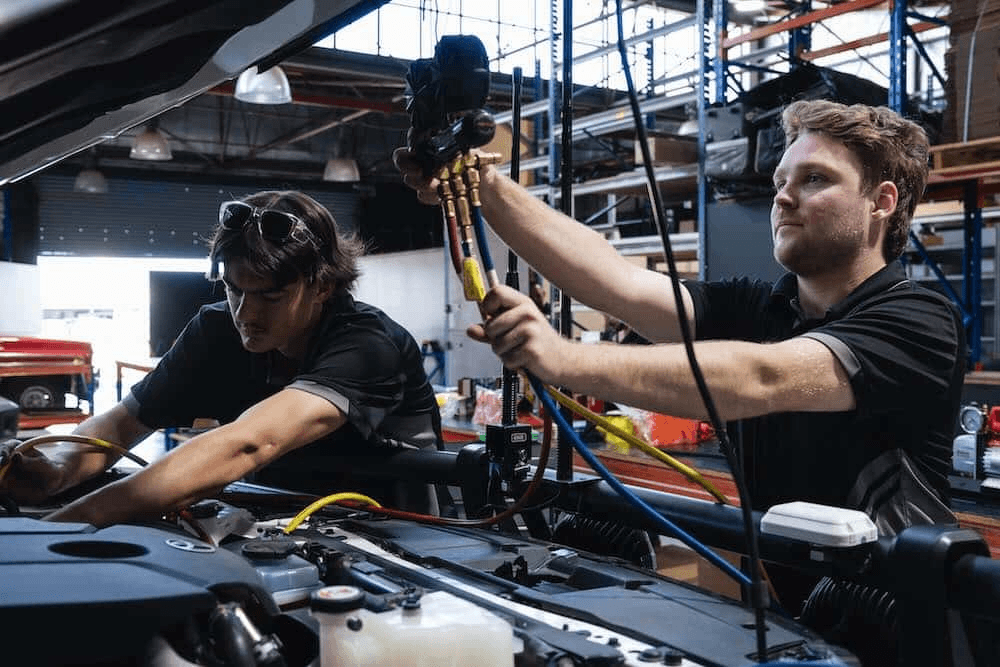 Technicians servicing a car AC system at American Auto Repair Center in Colonia NJ